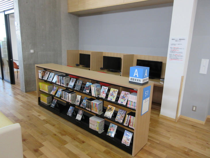 DVDが沢山収納された専用棚と仕切りのあるカウンターテーブルにデスプレイが3台並んで配置されている写真
