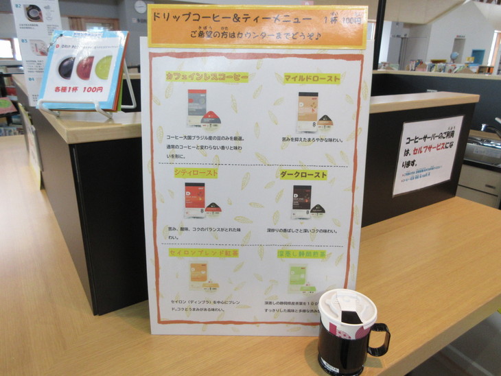 カフェカウンターテーブルの上に立てかけてあるメニュー表とコーヒーカップの写真