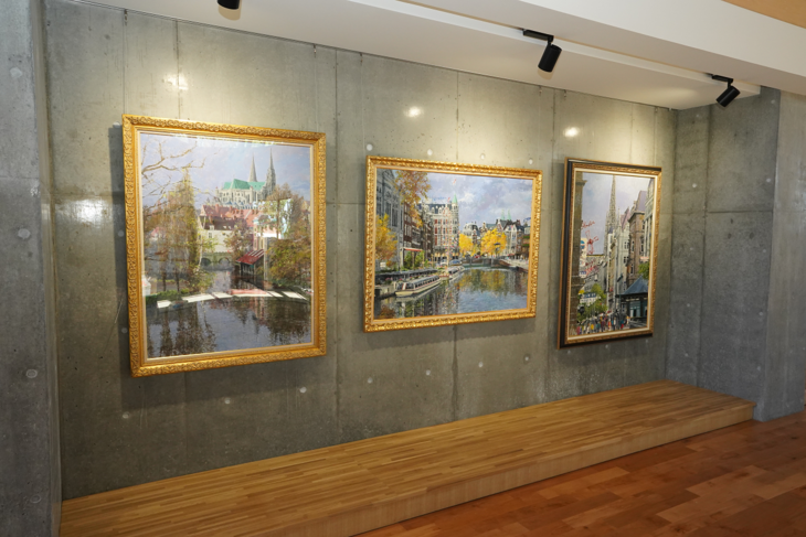 コンクリートの壁に掛けられた小田切訓先生の3枚の絵画の写真