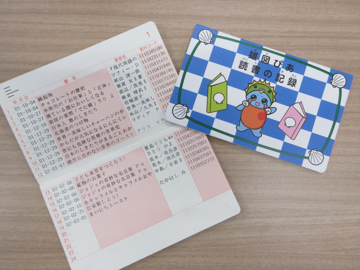 青と白の市松模様にキャラクターがプリントされた表紙の通帳と、見開きの通帳を並べた写真