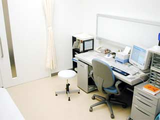 白い壁に囲まれ、机の上にパソコンや書類棚などが並んでいる診察室の写真