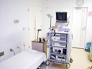 ベッドの横に、様々な機械やモニターが乗った棚が置かれている部屋の写真