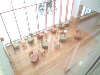 テーブルと椅子が並んだ、下の階のラウンジを見下ろすように撮影した写真