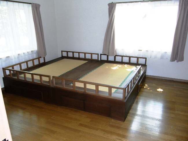 ダブルサイズのベッドが置かれた明るい寝室の写真